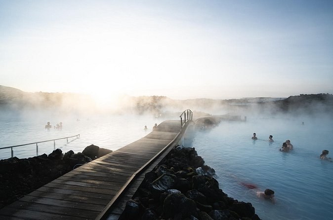 A wooden walkway leading out into a steaming milky-blue lagoon