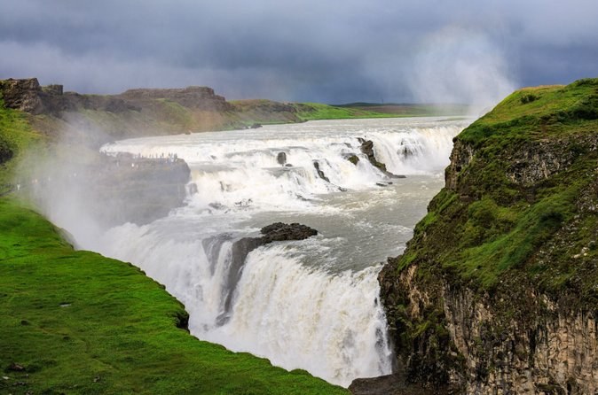 Gullfoss's upper and lower drops under a stormy sky, spray rising from the canyon