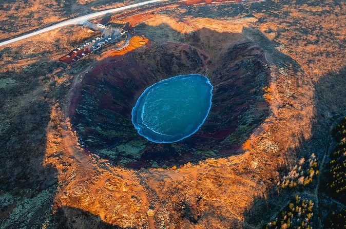 Kerid crater seen from the air, a blue lake in a ring of rust-coloured scoria