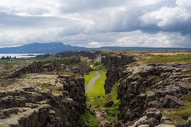 A footpath running along the floor of a grassy rift between two lava walls