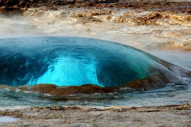The turquoise water dome that swells over a geyser's vent a moment before it erupts