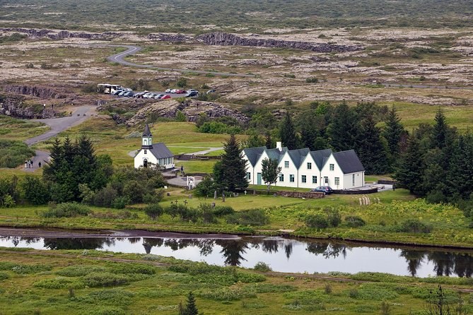 The small white church and the five gabled houses at Thingvellir beside a still river