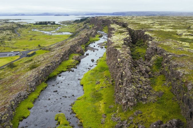 A water-filled fissure cutting through green moss and lava, seen from above
